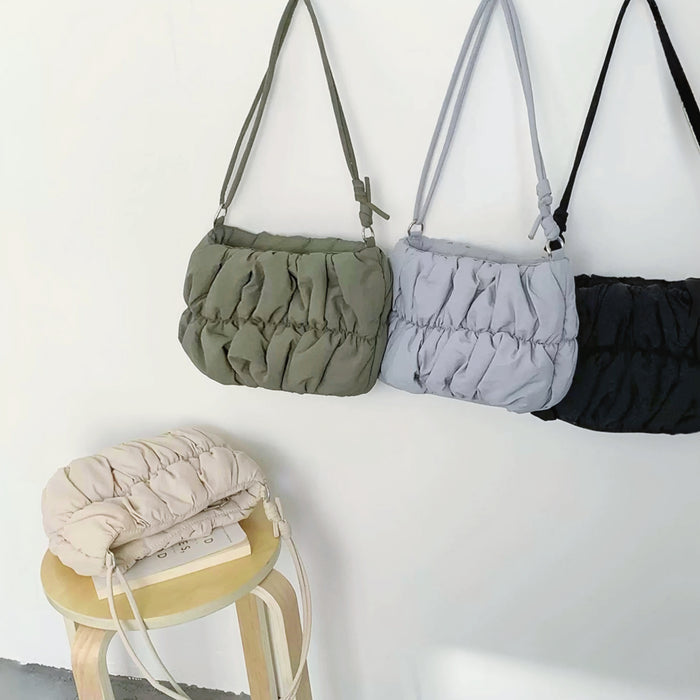 Angled view of three colors of Pleated Cloud Bags hanging on the wall, great for everyday carry and travel.