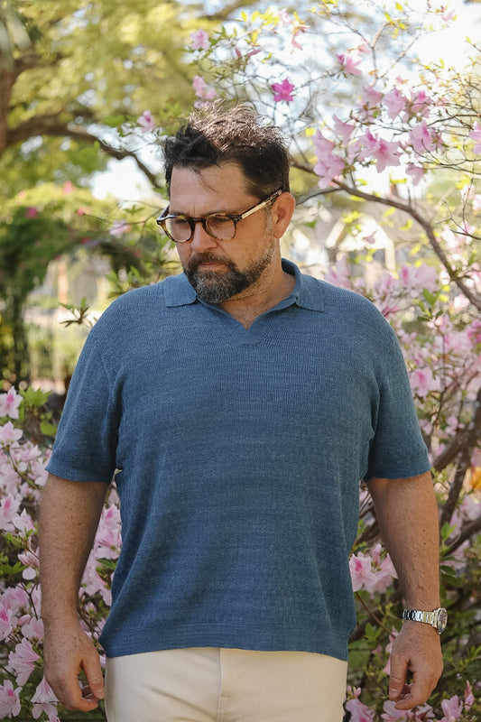 Man wearing a blue polo shirt standing in front of cherry blossom trees