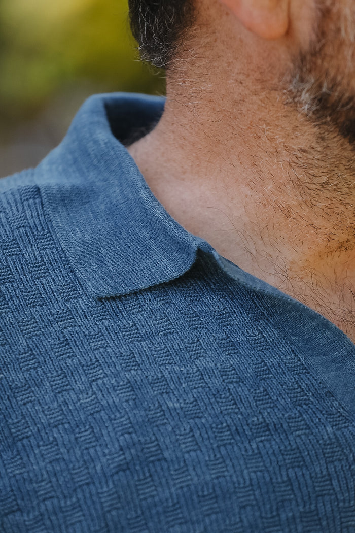 Close-up of a person wearing a textured blue shirt with a blurred background