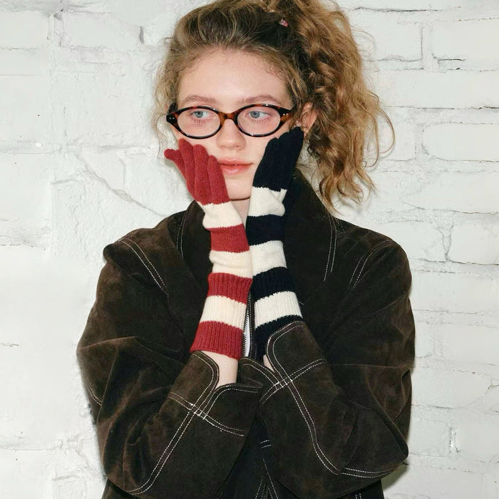 Model wearing bold stripe knit gloves, red/cream and navy/cream stripes; warm winter accessory for outdoors.