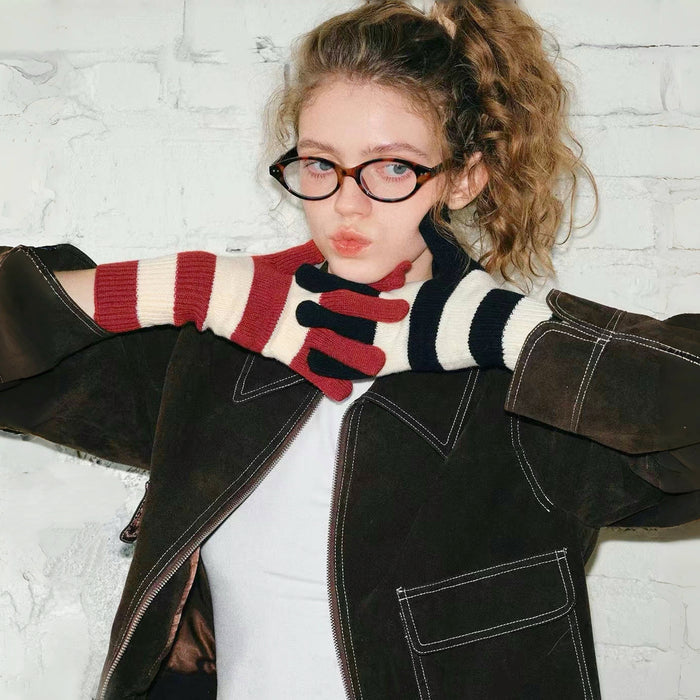 Model wearing bold stripe knit gloves with red, cream, and navy bands; cozy for cold-day street outfits.