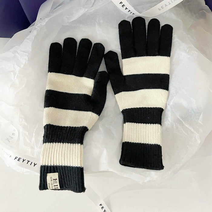 Flat lay bold stripe knit gloves in black and cream with ribbed cuffs; classic striped winter gloves.