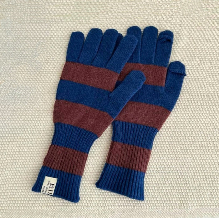 Bold stripe knit gloves in blue and brown, laid on textured fabric; cozy knit for chilly days.