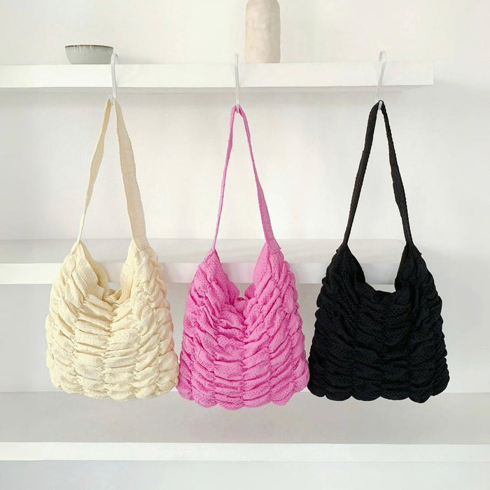Close-up of Three polyester Bubble Pleat Bags in cream, pink, and black.