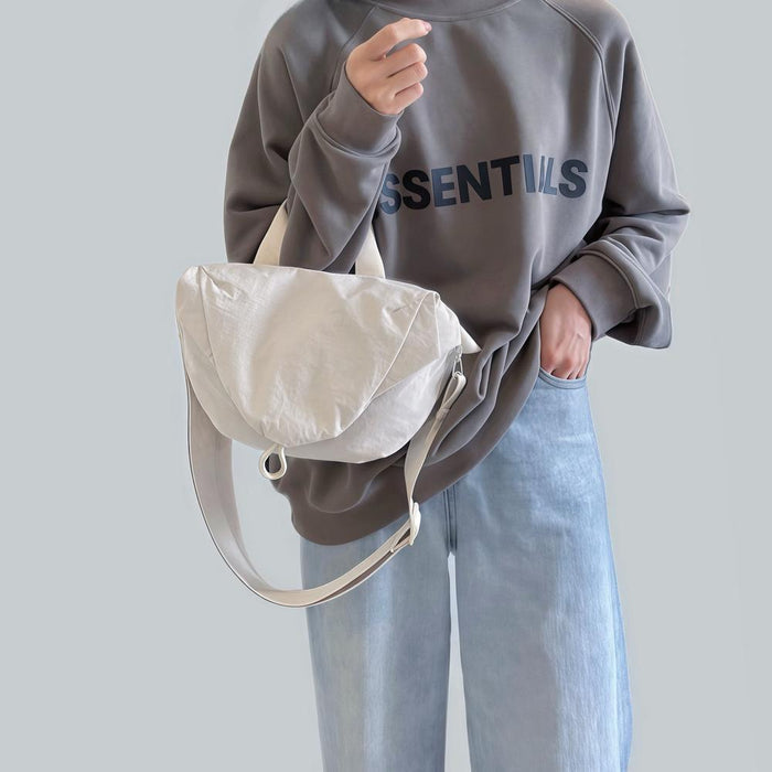 Model holding the off-white nylon bag, showcasing its soft slouchy shape and top handle.