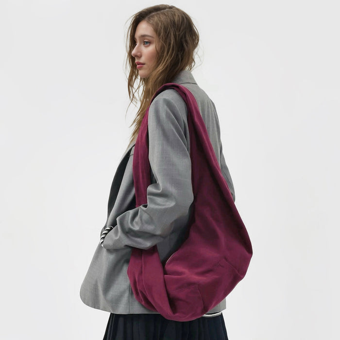 Model styling the rich burgundy corduroy crescent bag with a grey blazer.