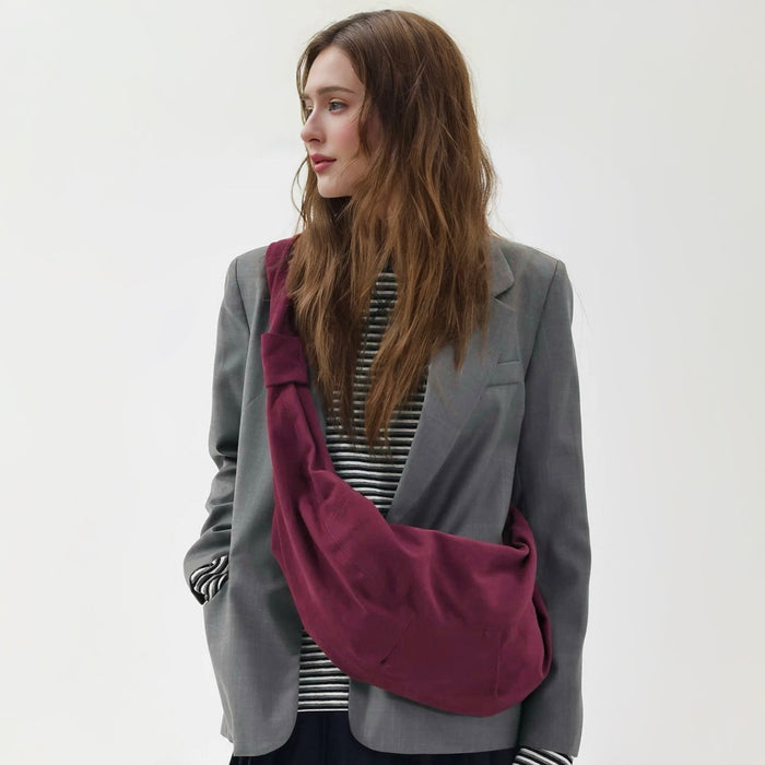 Frontal view of the burgundy corduroy crescent bag on a model.