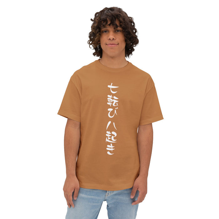 A men with curly brown hair wearing a tan drop shoulder t-shirt with vertical white Japanese characters, paired with light blue jeans, against a plain white background. | AH Urban Wear PK