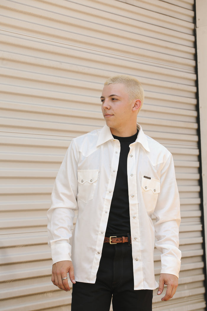 Man wearing white Lindell Tencel cotton shirt over black tee against beige metal wall