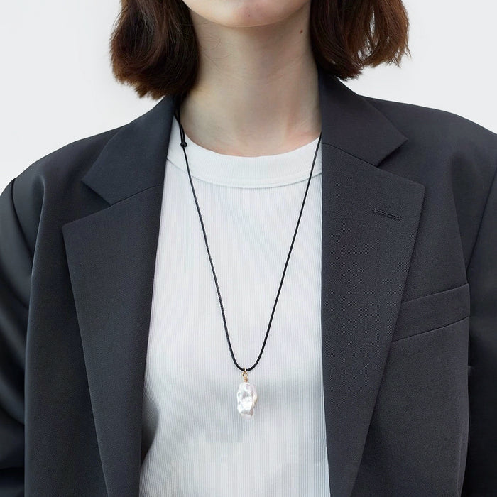 Model wearing silver lustrous drop pendant necklace, minimalist elegant jewelry style