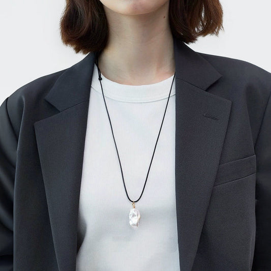 Model wearing silver lustrous drop pendant necklace, minimalist elegant jewelry style