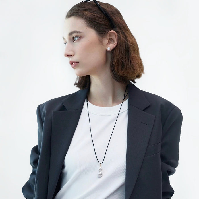 Flat lay of silver teardrop pendant necklace on white fabric, polished jewelry view