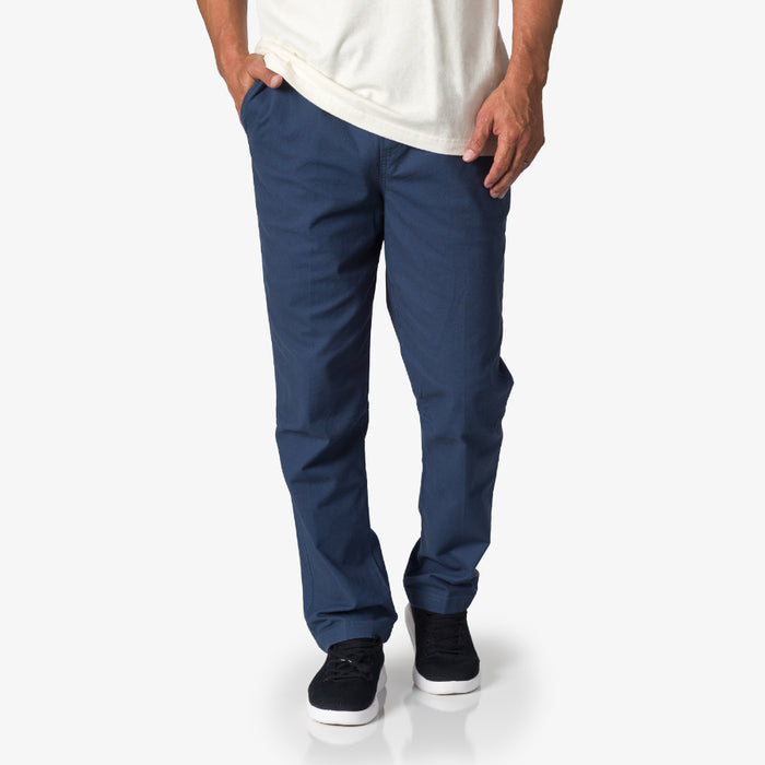 Men wearing navy Matthew Twill Pant showing full front view with black REEF sneakers facing forward for beach comfort.