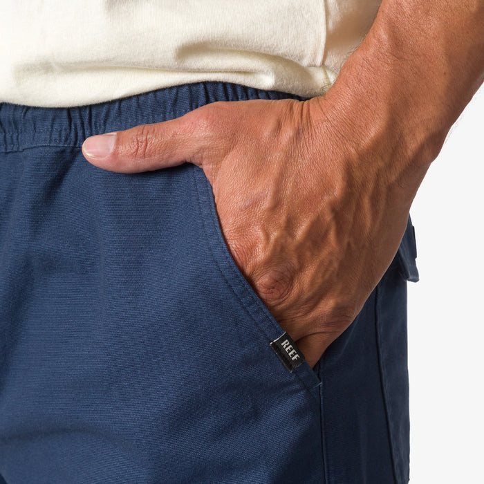 Close-up of a man's hand in the right pocket of navy blue Matthew Twill Pant with REEF tag visible