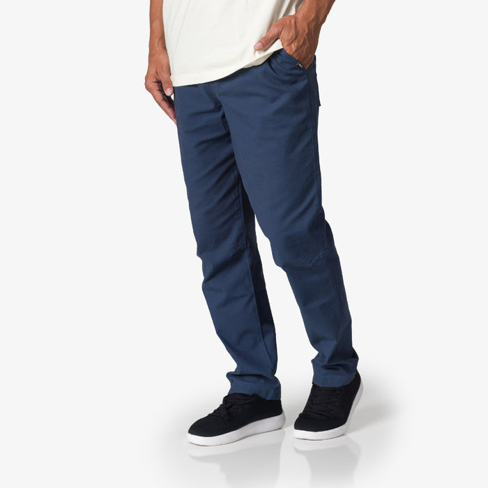Men wearing blue Matthew Twill Pant, standing with right side facing, paired with black casual shoes with white soles.
