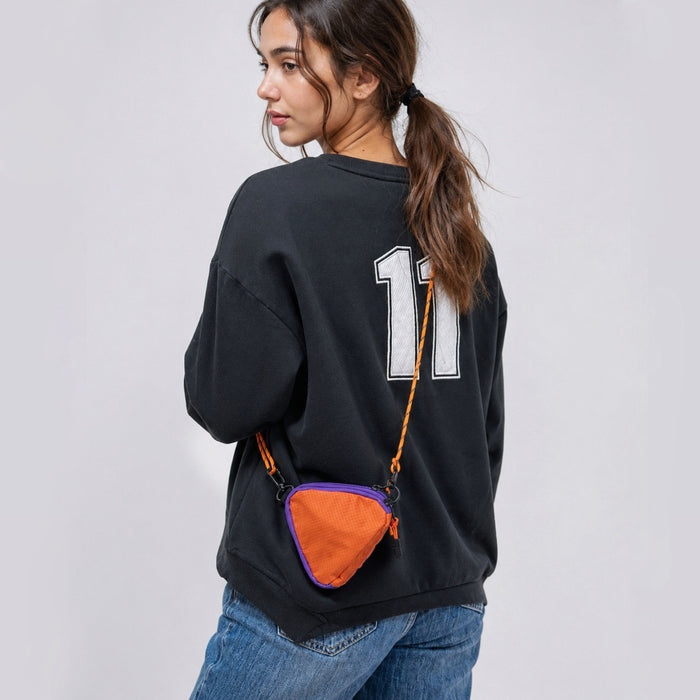A model wearing an orange triangle mini bag as a crossbody, highlighting the geometric style impact.