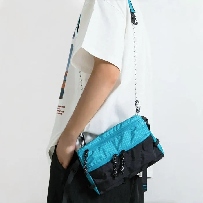 Model styling blue and black utility sling bag, functional street style accessory.