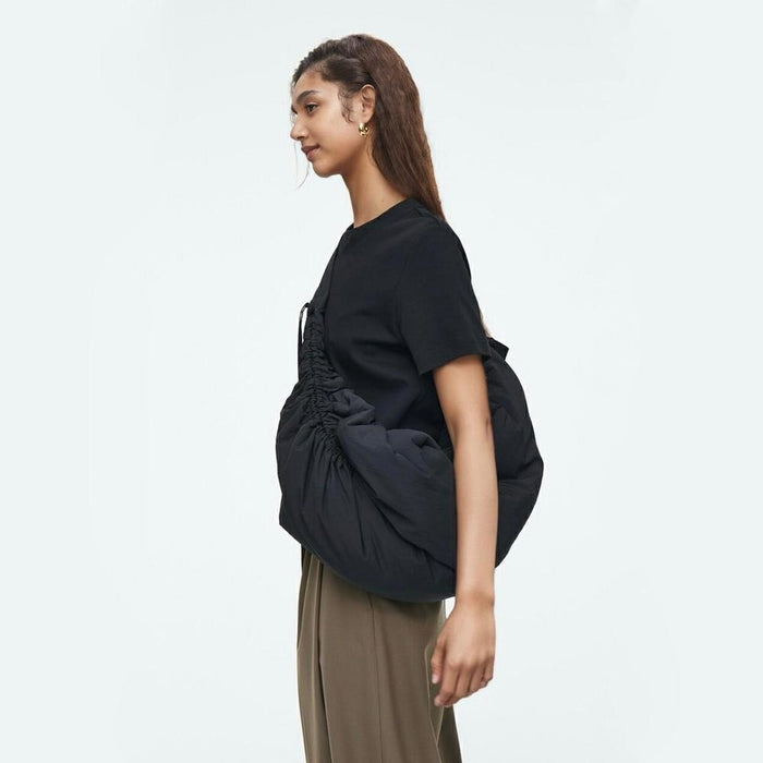 Side view of the black puffy nylon bag, highlighting its extra-roomy capacity and soft texture.