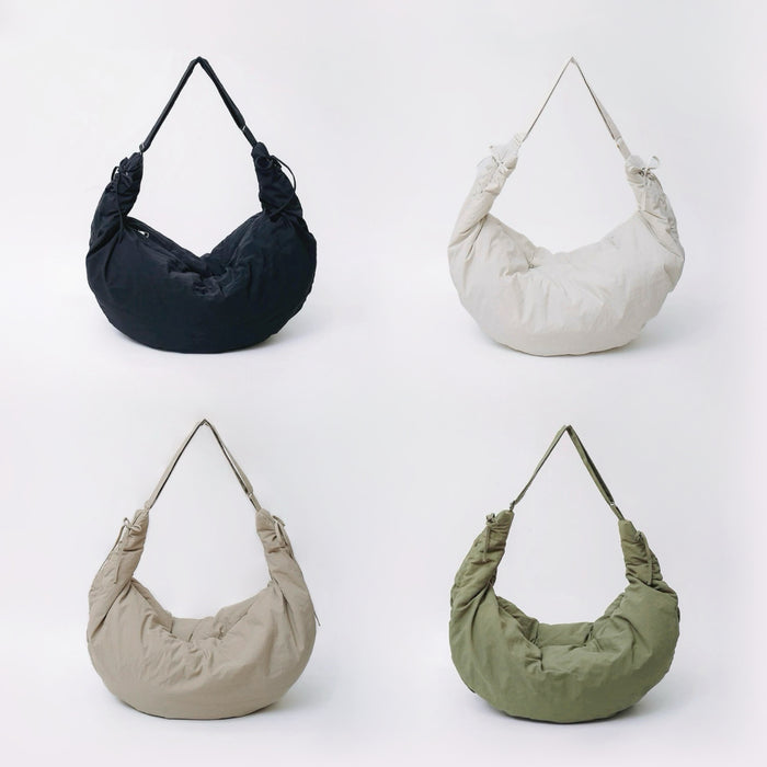 Group shot of the duvet crescent bag in black, off-white, khaki, and olive green.
