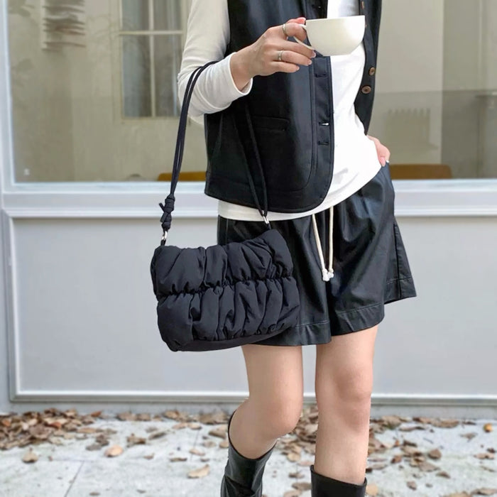 Model carrying a black pleated cloud bag handheld, easy for commuting and weekends.