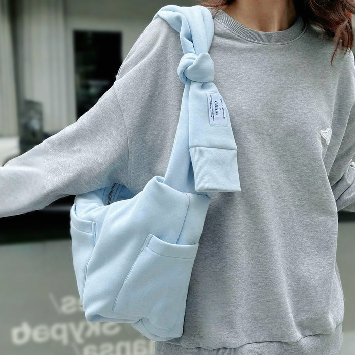 Model carrying a blue Twist & Tie Sleeve Bag on the shoulder, easy for commuting and weekends.