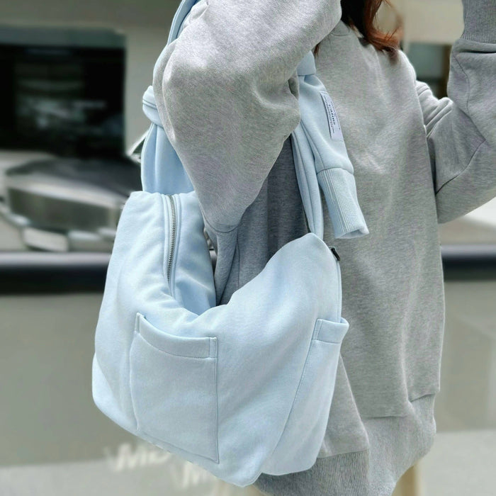 Model carrying a Twist & Tie Sleeve Bag in blue, ideal for city walks and gifting.