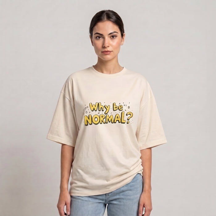 A woman modeling a cream-colored drop shoulder t-shirt with the text 'Why be NORMAL?' printed in yellow and black on the front, paired with light blue jeans, against a plain light gray background | AH Urban Wear